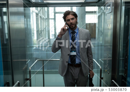 Caucasian businessman talking on the mobile phone in modern elevator at office Caucasian businessman talking on the mobile phone in modern elevator at office 53003870