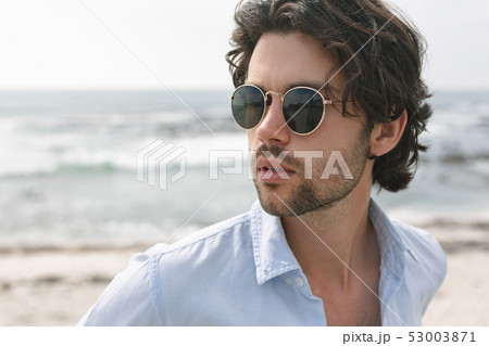 Caucasian man standing at beach on a sunny day Caucasian man standing at beach on a sunny day 53003871