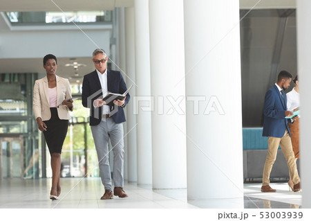 Businesswoman and businessman interacting with each other while walking in lobby office 53003939