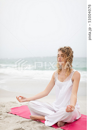 Woman performing yoga on the beach 53004076