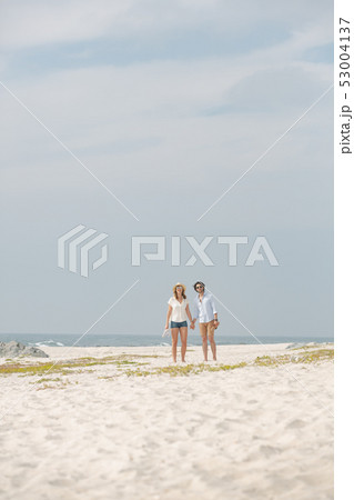 Caucasian couple standing at beach on a sunny day Caucasian couple standing at beach on a sunny day 53004137