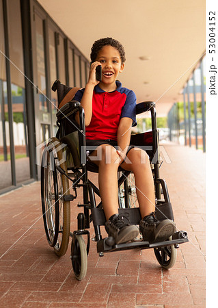 Happy disabled schoolboy talking on mobile phone in corridor Happy disabled schoolboy talking on mobile phone in corridor 53004152