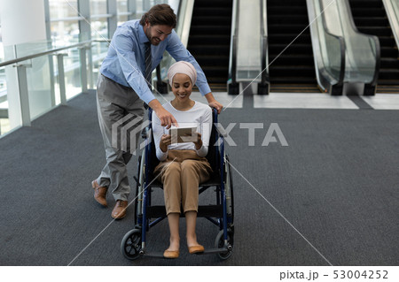 Disabled young mixed-race female executive with Caucasian businessman discussing over digital tablet Disabled young mixed-race female executive with Caucasian businessman discussing over digital tablet 53004252