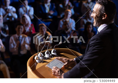 Businessman standing and giving presentation in the auditorium  53004449