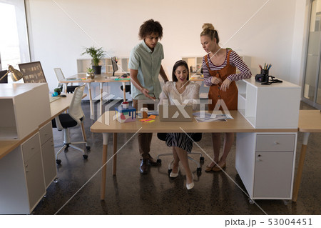 Business colleagues discussing over laptop in office 53004451