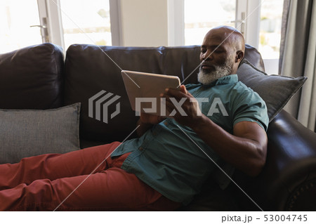 Senior man using digital tablet in living room Senior man using digital tablet in living room 53004745
