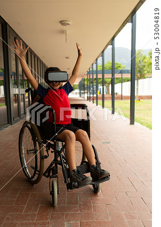 Happy disabled schoolboy using virtual reality headset in corridor Happy disabled schoolboy using virtual reality headset in corridor 53004819