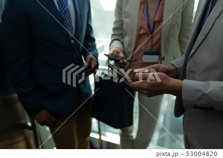 Multi-ethnic business colleague discussing over the digital tablet in elevator 53004820