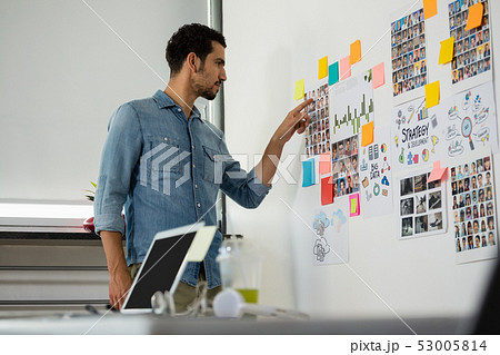 Man pointing at photographs in office Man pointing at photographs in office 53005814
