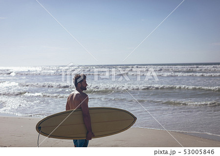 Male surfer with a surfboard standing on a beach Male surfer with a surfboard standing on a beach 53005846