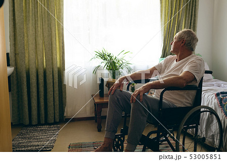 Male patient looking outside the window while sitting in wheelchair Male patient looking outside the window while sitting in wheelchair 53005851