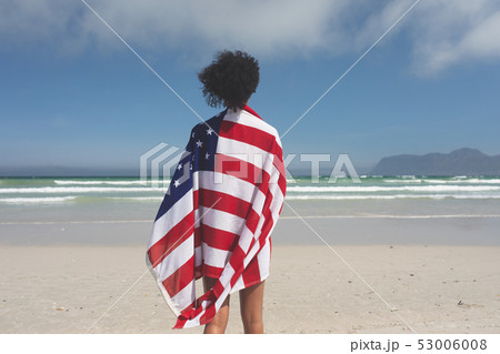 Woman wrapped american flag at beach 53006008