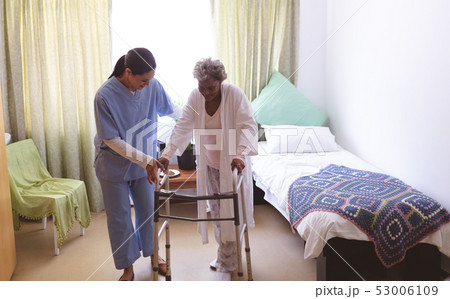 Female nurse helping senior female patient to stand with walker Female nurse helping senior female patient to stand with walker 53006109