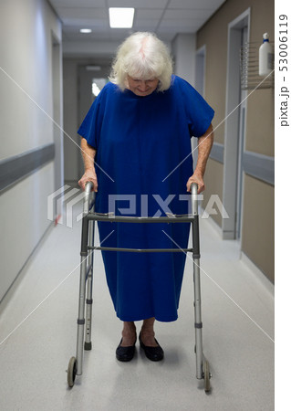 Senior female patient walking with walker in clinic 53006119