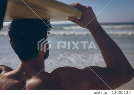 Male surfer carrying his surfboard at beach Male surfer carrying his surfboard at beach 53006139