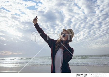 Beautiful woman taking selfie at beach  53006228