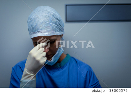 Upset female surgeon standing while leaning against the operating room door 53006575