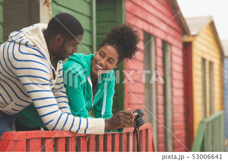 Couple using digital camera while standing at beach hut 53006641