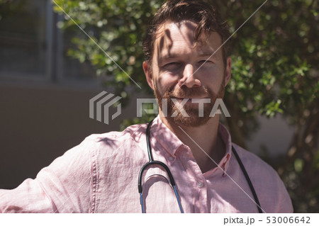 Confident male doctor sitting on bench outside the nursing home 53006642