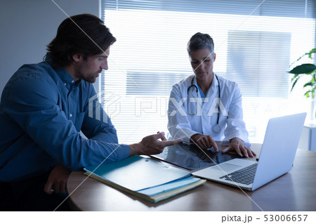 Mature female doctor and patient discussing over x-ray Mature female doctor and patient discussing over x-ray 53006657