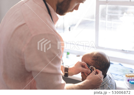 Male doctor applying hearing aid to senior man ear Male doctor applying hearing aid to senior man ear 53006872