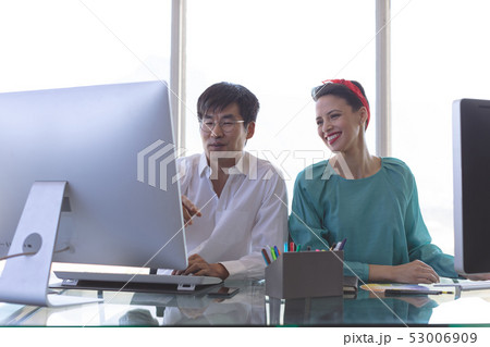 Business people discussing over computer at desk in office Business people discussing over computer at desk in office 53006909