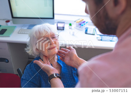 Male doctor checking senior female patient in clinic 53007151