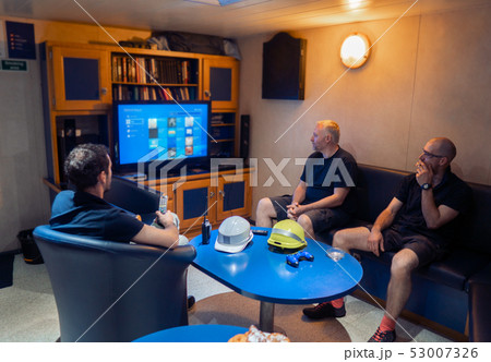 Happy team of ship officers watch TV onboard of vessel Happy team of ship officers watch TV onboard of vessel 53007326