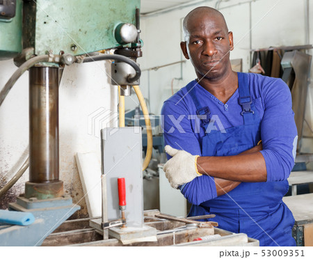 African American glazier working with glass on stationary drilling machine African American glazier working with glass on stationary drilling machine 53009351
