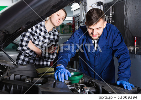 Two masters are replacing the oil in the car in workshop. Two masters are replacing the oil in the car in workshop. 53009394
