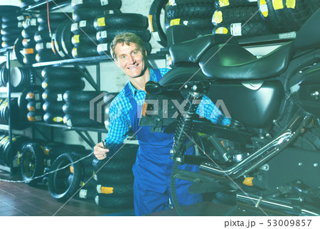 man in coveralls checking motorcycle man in coveralls checking motorcycle 53009857