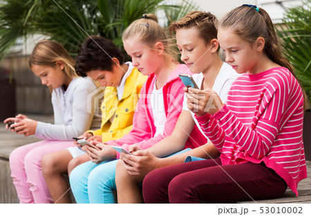 Children playing on smartphone outdoors Children playing on smartphone outdoors 53010002