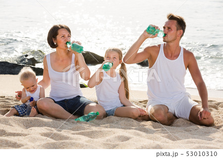 family drinking water on the beach. family drinking water on the beach. 53010310