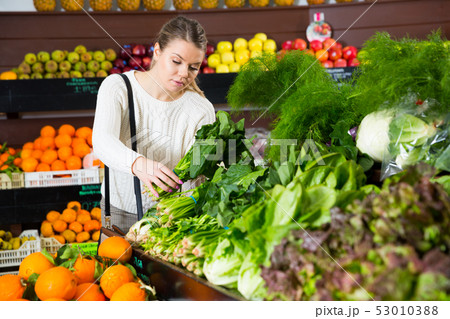 Female customer choosing greens and letuce on the supermarket 53010388