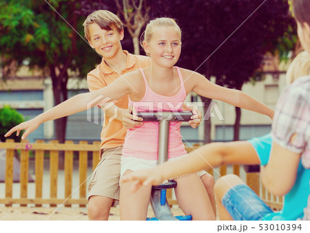 Cheerful children are teetering on the swing 53010394