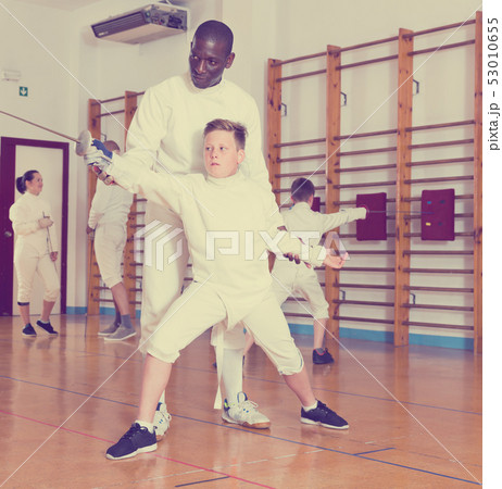 Fencing instructor with young fencers in training room Fencing instructor with young fencers in training room 53010655