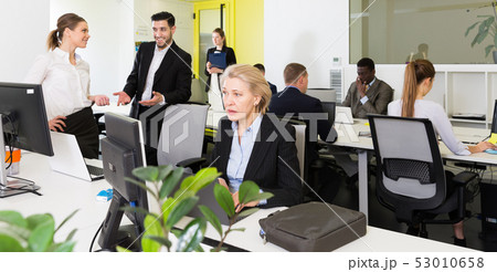 Coworkers engaged in open plan office 53010658
