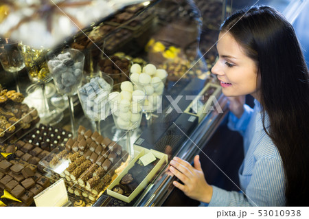 Smiling girl choosing chocolates. 53010938