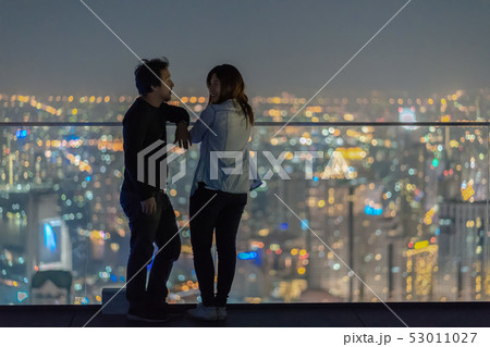 Romantic Couple standing on the rooftop from bangkok modern building at night time over the photo blurred of cityscape background, Lover and calentine holiday concept, low light Romantic Couple standing on the rooftop from bangkok modern building at night time over the photo blurred of cityscape background, Lover and calentine holiday concept, low light 53011027