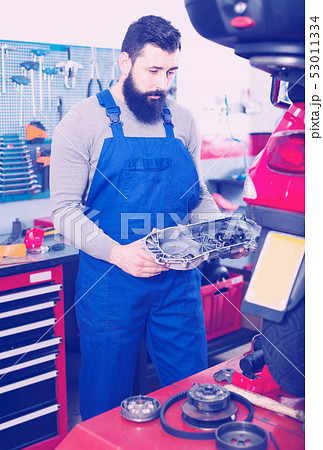 concentrated man worker working at restoring motorbike in workshop concentrated man worker working at restoring motorbike in workshop 53011334