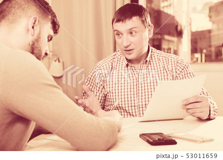 Focused man with partner reading papers at table Focused man with partner reading papers at table 53011659