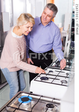 smiling mature couple chooses in shop of household appliances gas stove with oven smiling mature couple chooses in shop of household appliances gas stove with oven 53011952