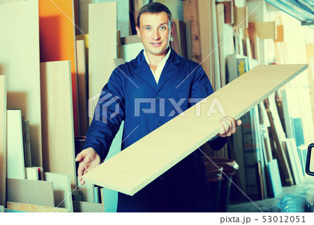 smiling male worker standing with plywood pieces 53012051