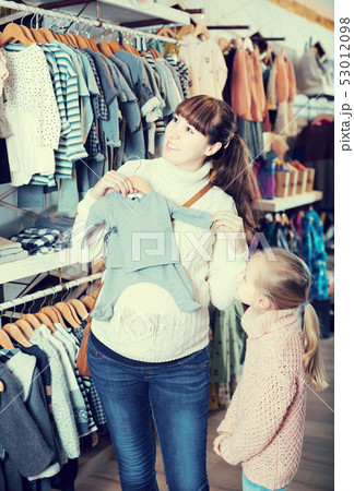 Pregnant mother and daughter choosing romper suit for baby in children’s clothes shop Pregnant mother and daughter choosing romper suit for baby in children’s clothes shop 53012098