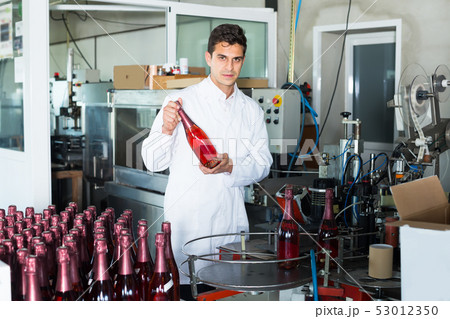 concentrated man employee standing in final section of wine production on factory 53012350