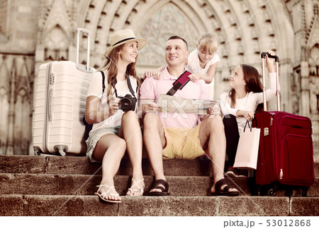 Happy family of fours tourists sitting on old cathedral steps 53012868