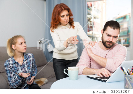 Upset young man working at laptop, young sister and mother 53013207