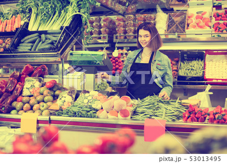 Woman seller is weighing fruit and vegetables Woman seller is weighing fruit and vegetables 53013495