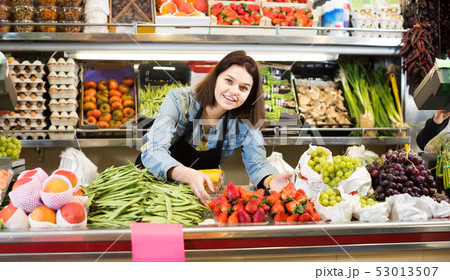 Female shopping assistant demonstrating assortment of grocery shop Female shopping assistant demonstrating assortment of grocery shop 53013507