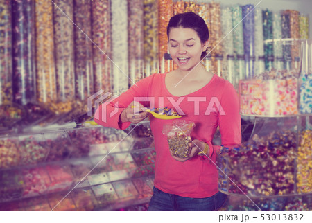 Shopgirl in store is picking up candies Shopgirl in store is picking up candies 53013832
